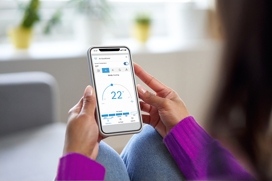 Hand holding a smartphone running the air conditioning control app